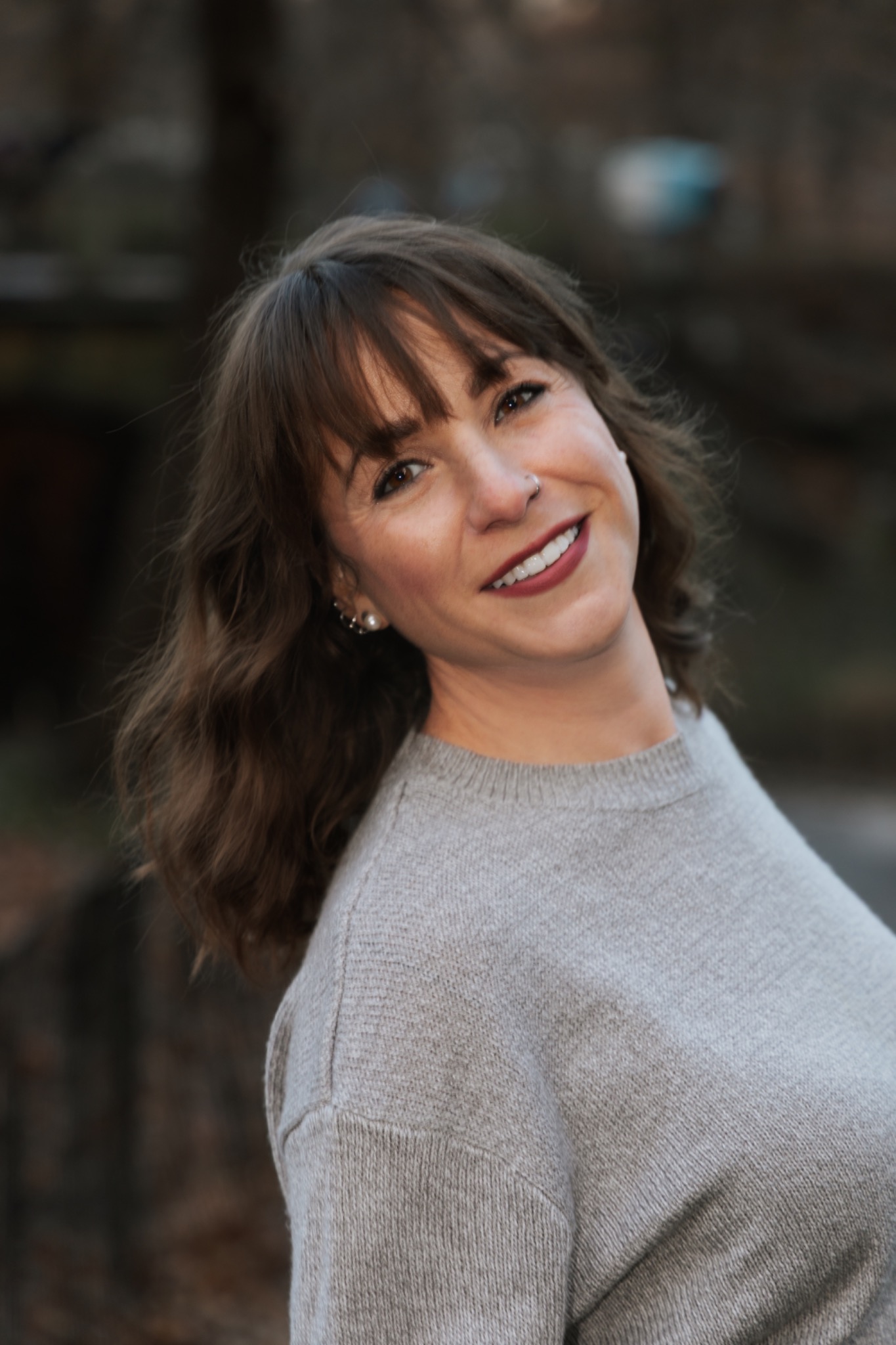 Portrait — smiling woman with wavy hair, warm grey sweater